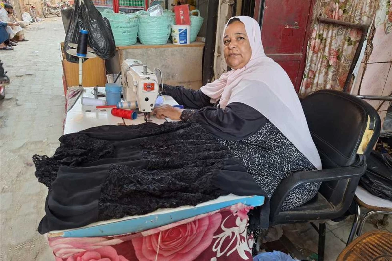 بتشتغل 12 ساعة.. قصة كفاح سيدة سوهاجية مع تربية 4 أبناء: بشتغل خياطة وحلمي أدخل بنتي الكلية على طاولة خشبية تحمل ماكينة خياطة في إحدي شوارع مدينة سوهاج، تجلس السيدة ام عبدالرحمن عل
