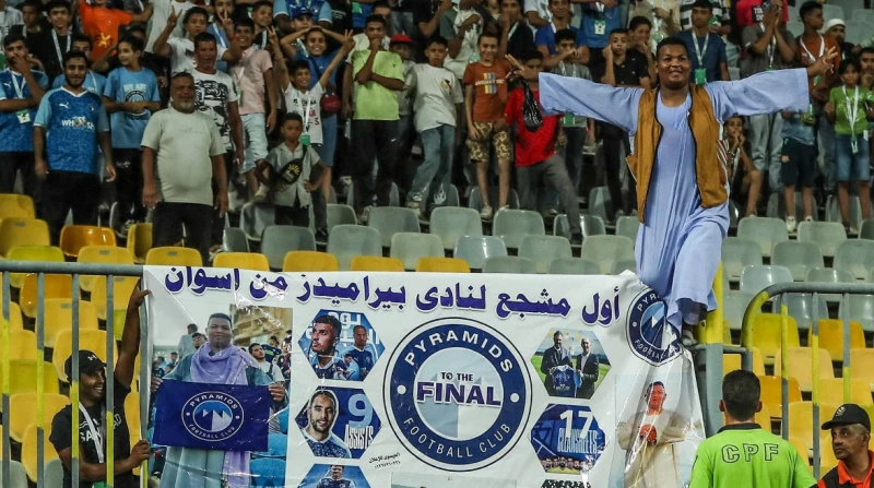 من أسوان إلى برج العرب.. مشجع بيراميدز يروي كواليس لافتة الكأس وجه أسمر، وجلباب صعيدي، وعلم باللونين الأبيض والأزرق ملفوف على رقبته، ولافتة كبيرة